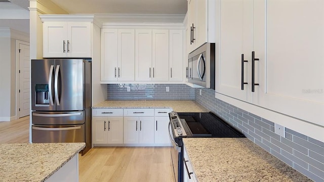 kitchen with white cabinets, tasteful backsplash, stainless steel appliances, and light wood-type flooring