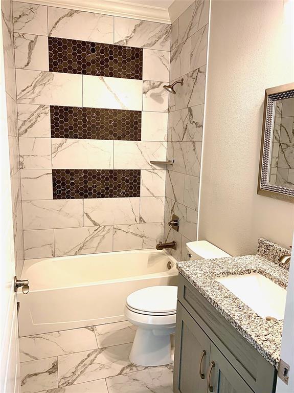 full bathroom featuring tiled shower / bath, toilet, tile floors, and vanity