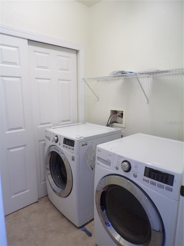 laundry area featuring light tile flooring, washer hookup, and washing machine and clothes dryer