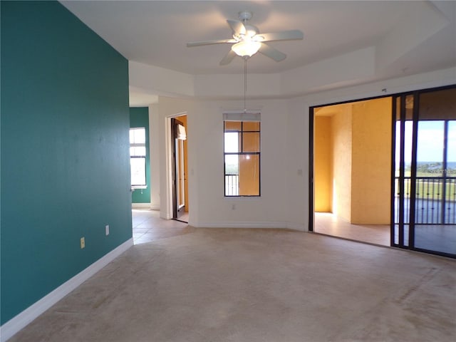 unfurnished room featuring light carpet, a raised ceiling, and ceiling fan