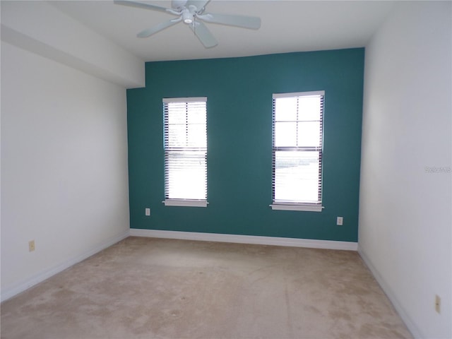 spare room with light carpet, ceiling fan, and a wealth of natural light