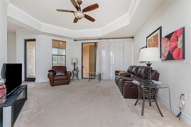 carpeted living room with crown molding, ceiling fan, and a tray ceiling