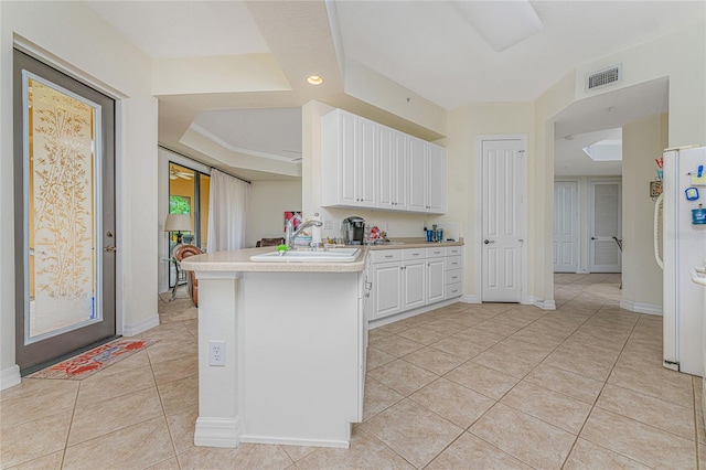 kitchen featuring white fridge, light tile flooring, kitchen peninsula, white cabinetry, and sink