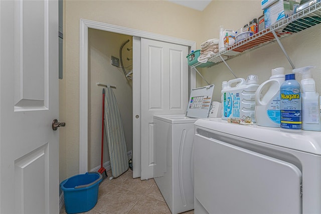 clothes washing area with light tile floors and washer and dryer