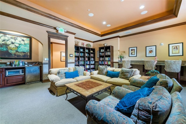 carpeted living room featuring crown molding, a raised ceiling, and a fireplace