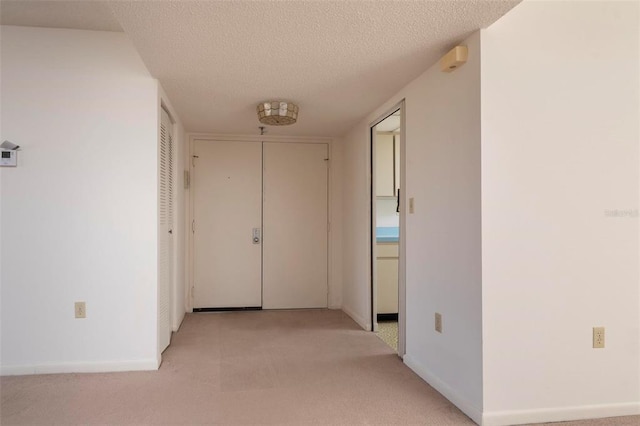 corridor with a textured ceiling and light colored carpet