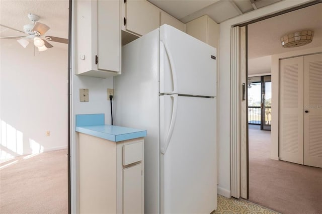 kitchen featuring light carpet, white fridge, ceiling fan, and white cabinetry