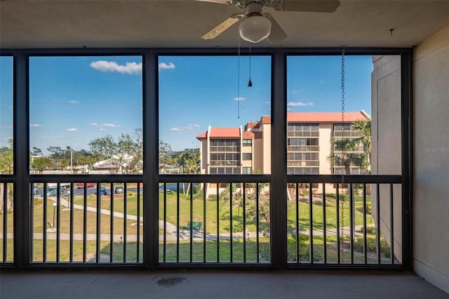 unfurnished sunroom featuring ceiling fan and a wealth of natural light