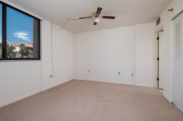 empty room featuring light colored carpet, ceiling fan, and a textured ceiling