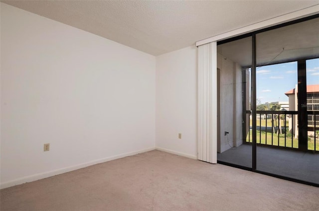 spare room with light carpet, a wall of windows, and a textured ceiling