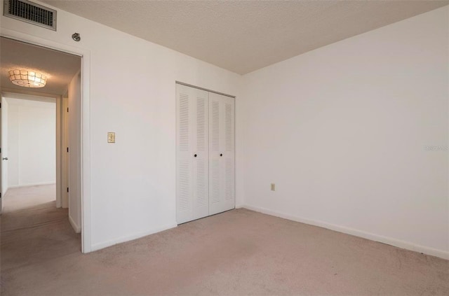 unfurnished bedroom with a closet and light colored carpet