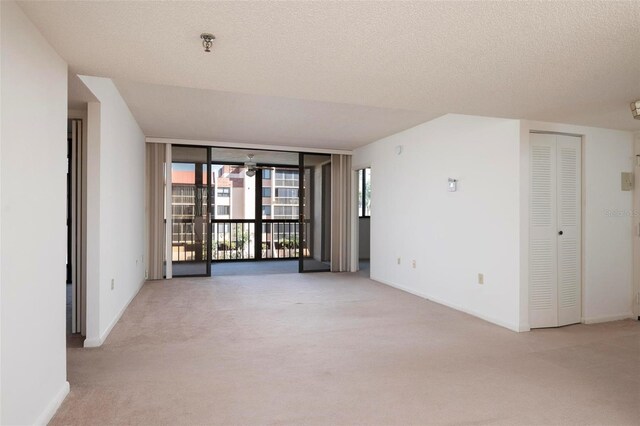3006 Caring Way Unit 325, Port Charlotte, FL 33952 - carpeted empty room featuring a pendent fire sprinkler, a wall of windows, baseboards, and a textured ceiling