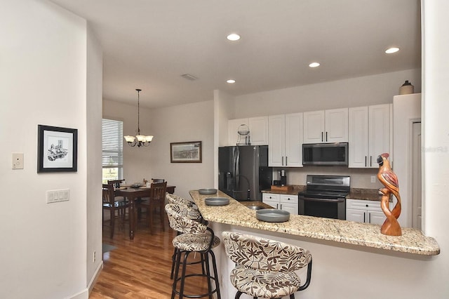 kitchen featuring white cabinets, light hardwood / wood-style flooring, a breakfast bar area, electric range oven, and an inviting chandelier