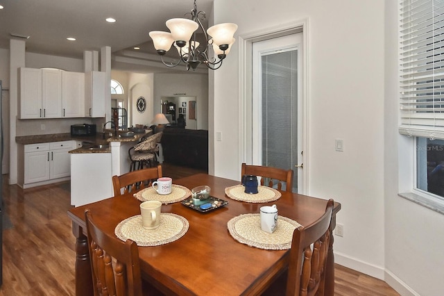 dining room featuring an inviting chandelier, sink, and hardwood / wood-style flooring