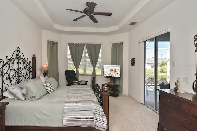 bedroom featuring ceiling fan, a tray ceiling, and access to exterior