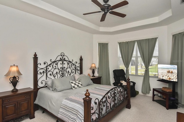 bedroom featuring ceiling fan, a raised ceiling, and light colored carpet