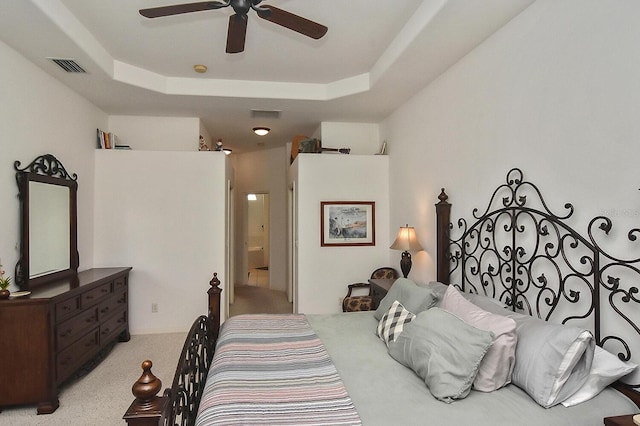 bedroom featuring ceiling fan, light carpet, and a raised ceiling