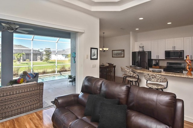 living room featuring ceiling fan with notable chandelier and light hardwood / wood-style flooring