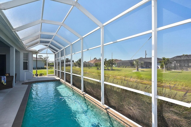 view of swimming pool featuring a lawn and a lanai