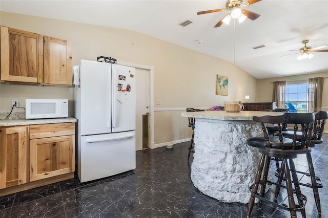 kitchen featuring ceiling fan, vaulted ceiling, white appliances, and dark tile flooring