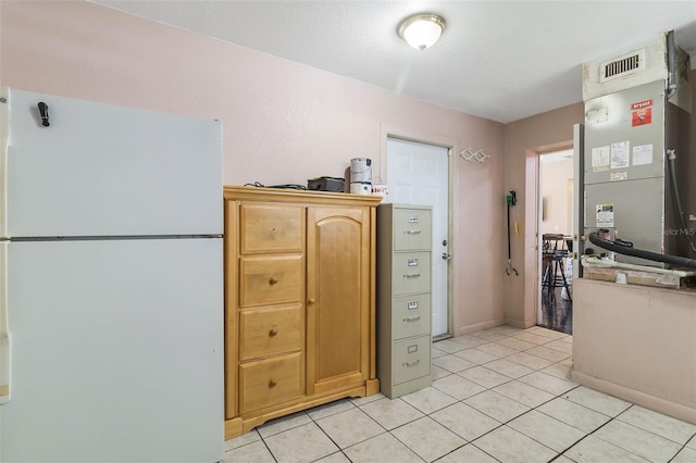 kitchen with light tile flooring, heating utilities, and white refrigerator