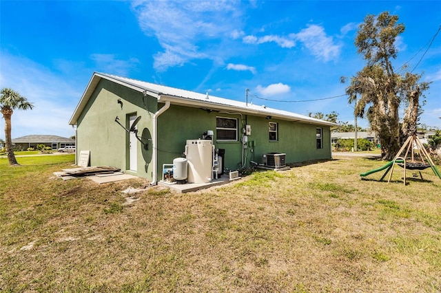 rear view of property featuring a lawn, a playground, and central AC