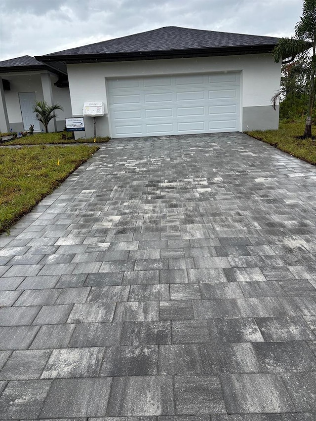 8285 Agate St, Port Charlotte, FL 33981 - view of front of property with decorative driveway, roof with shingles, stucco siding, an attached garage, and a front lawn