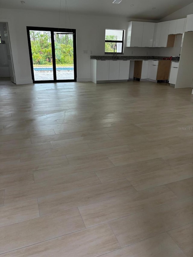 8285 Agate St, Port Charlotte, FL 33981 - unfurnished living room with a sink, baseboards, light wood-type flooring, and lofted ceiling