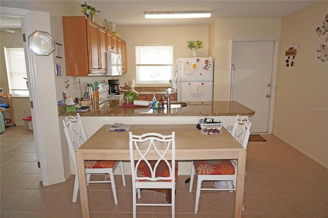 kitchen with white appliances, stone countertops, sink, and light tile floors