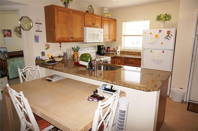 kitchen featuring kitchen peninsula, white appliances, sink, light tile floors, and light stone countertops