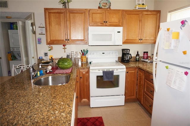 kitchen featuring white appliances, dark stone countertops, sink, and light tile floors