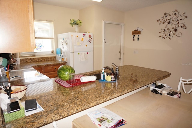 kitchen featuring dark stone countertops and white refrigerator