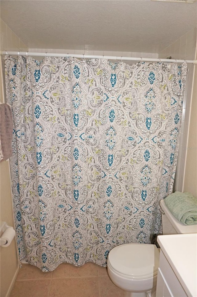 bathroom featuring toilet, tile flooring, a textured ceiling, and vanity