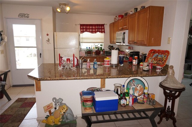 kitchen featuring white appliances, dark stone counters, and a healthy amount of sunlight