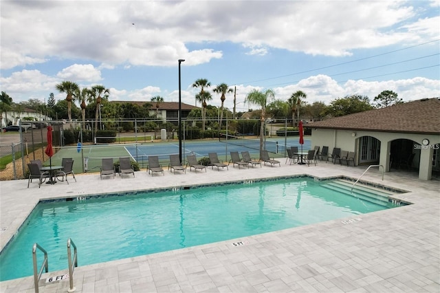 view of swimming pool with a patio and tennis court