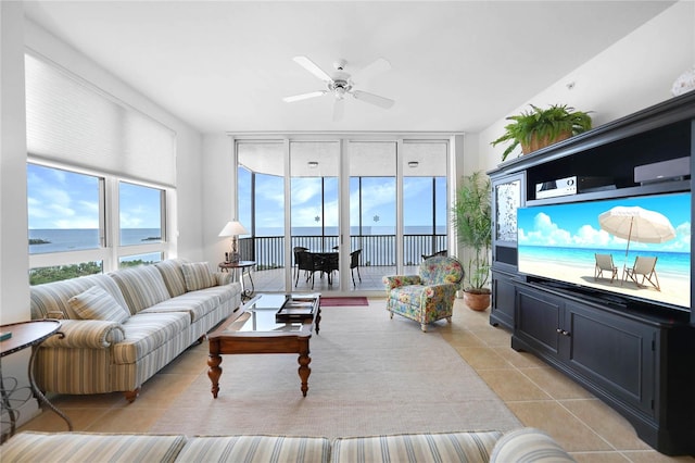 living room featuring a water view, expansive windows, ceiling fan, and light tile floors