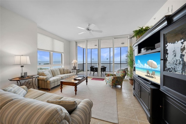 tiled living room with a water view, expansive windows, and ceiling fan