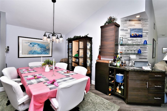 dining room featuring an inviting chandelier, sink, vaulted ceiling, and light hardwood / wood-style flooring