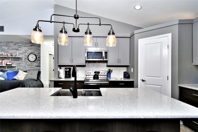 kitchen with vaulted ceiling, gray cabinets, appliances with stainless steel finishes, backsplash, and hanging light fixtures