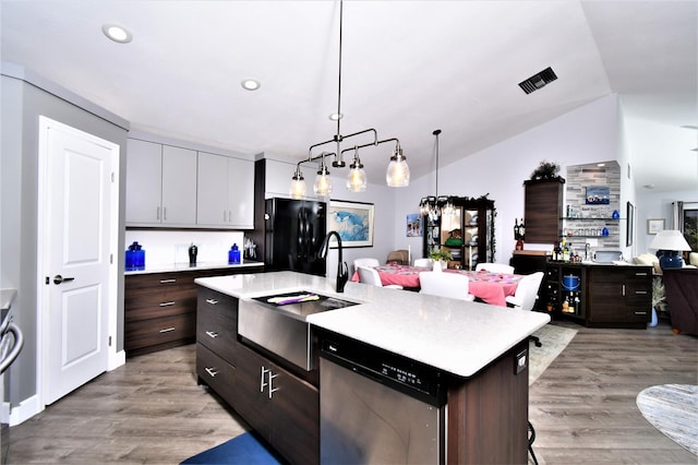 kitchen with an island with sink, light hardwood / wood-style floors, black refrigerator, lofted ceiling, and hanging light fixtures