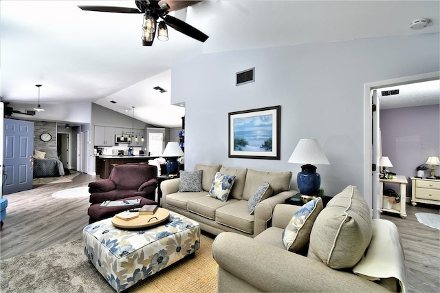 living room with light hardwood / wood-style floors, ceiling fan, and vaulted ceiling