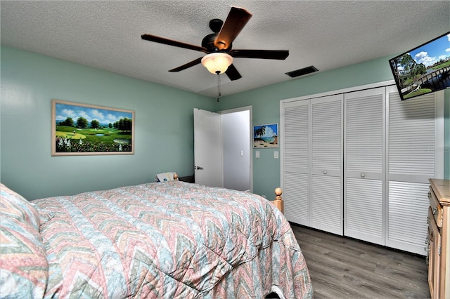 bedroom with a closet, a textured ceiling, dark hardwood / wood-style floors, and ceiling fan