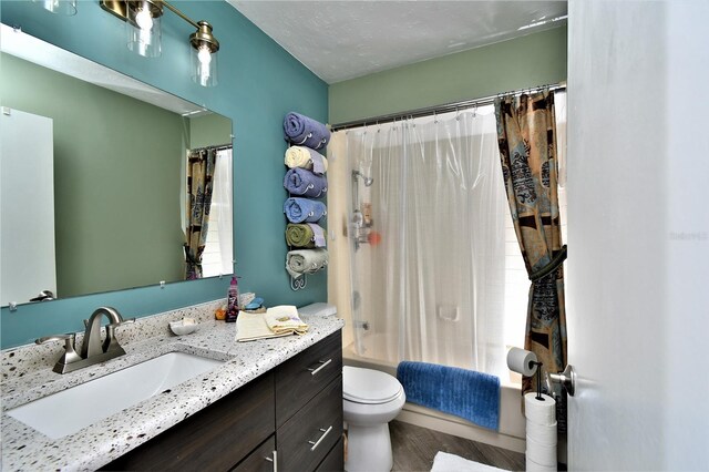 full bathroom featuring vanity, a textured ceiling, toilet, shower / bath combination with curtain, and hardwood / wood-style flooring