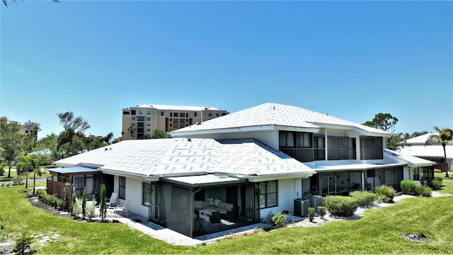 back of house featuring central AC, a sunroom, and a yard