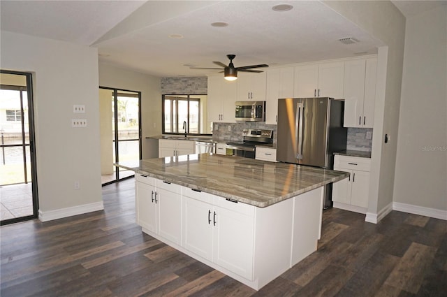 kitchen featuring dark hardwood / wood-style floors, ceiling fan, stainless steel appliances, light stone countertops, and white cabinetry