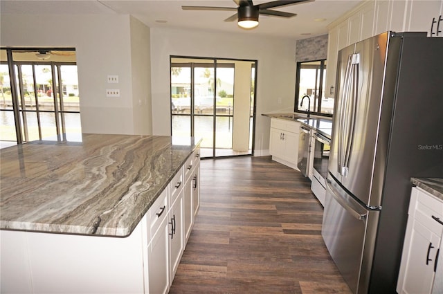 kitchen featuring light stone countertops, dark hardwood / wood-style floors, ceiling fan, white cabinets, and stainless steel refrigerator