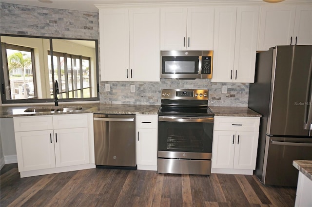 kitchen featuring dark wood-type flooring, appliances with stainless steel finishes, white cabinets, backsplash, and sink