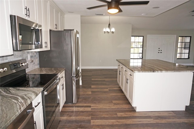 kitchen featuring stainless steel appliances, white cabinetry, dark wood-type flooring, and dark stone counters