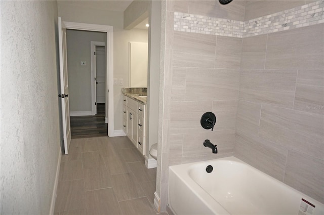 full bathroom featuring toilet, tile floors, tiled shower / bath combo, and vanity