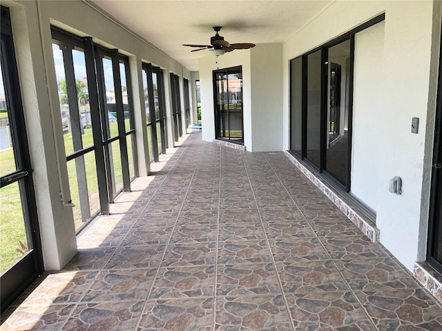 unfurnished sunroom featuring ceiling fan